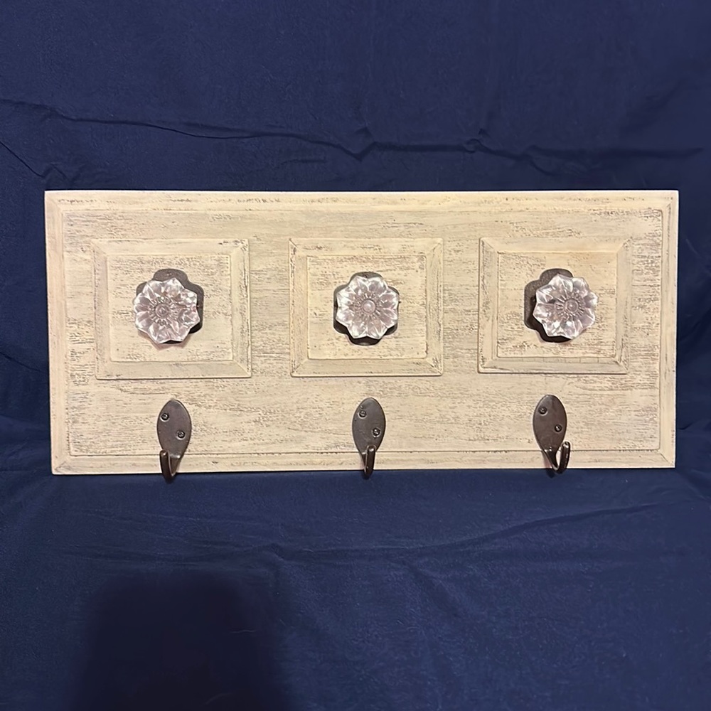 At Home America wall decor with 3 hooks 18X8. Has clear nobs above each hook.